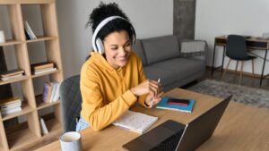 Mulher com fones de ouvido assistindo aula de um curso de espanhol online grátis em um notebook